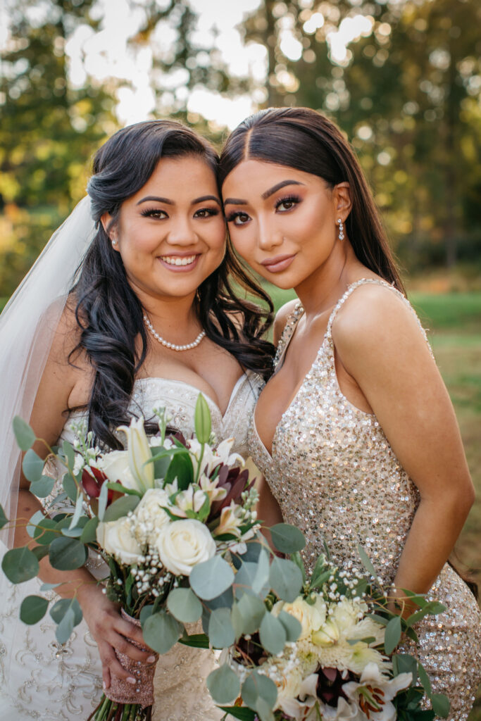 a bride and her bridesmaid stand smiling together on wedding day