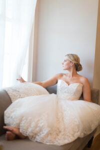 BRIDE IN POOFY WEDDING DRESS LOOKING OUT THE WINDOW STOICLY