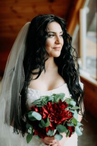 BRIDE IN VEIL HOLDING BOQUET AND LOOKING OUT THE WINDOW